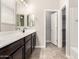 Bathroom with double sinks, dark cabinets and a separate doorway to the walk-in closet at 19726 W Woodlands Ave, Buckeye, AZ 85326