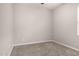 A minimalist bedroom featuring gray walls, plush carpet, and a window letting in natural light at 19726 W Woodlands Ave, Buckeye, AZ 85326