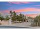 Charming home exterior with mature trees, brick driveway and desert landscaping against a colorful sky at sunset at 20041 W Pasadena Ave, Litchfield Park, AZ 85340