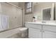 Well-lit bathroom featuring a shower-tub combo with sliding glass door, white cabinets, and window at 21152 W Sunrise Ln, Buckeye, AZ 85396
