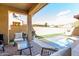 Relaxing covered patio with comfortable seating and a refreshing pool surrounded by lush greenery at 21152 W Sunrise Ln, Buckeye, AZ 85396