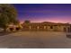 Large garage with three bays and a spacious driveway beneath a beautiful purple and orange dusk sky at 21470 E Orchard Ln, Queen Creek, AZ 85142