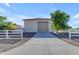 Garage exterior featuring a paved driveway, well-kept landscaping, and a charming white fence at 21470 E Orchard Ln, Queen Creek, AZ 85142
