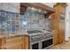 Kitchen with brick accents, custom tile backsplash, professional range, and granite countertops at 21470 E Orchard Ln, Queen Creek, AZ 85142