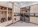 Well-lit mud room featuring custom cabinetry with mud bench, stainless steel washer and dryer, and decorative tiled floors at 21470 E Orchard Ln, Queen Creek, AZ 85142