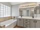 Bathroom featuring double sinks, a soaking tub, and natural lighting at 2313 E Gondola Ln, Gilbert, AZ 85234