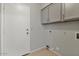 Functional laundry area with bright cabinets, white door, and utility connections at 2313 E Gondola Ln, Gilbert, AZ 85234