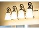 Close-up of a four-bulb bathroom vanity light fixture with frosted shades and decorative wrought iron accents at 23216 N Gaviota Dr, Sun City West, AZ 85375