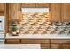 Kitchen with oak cabinets, mosaic backsplash, and a modern cooktop at 23216 N Gaviota Dr, Sun City West, AZ 85375