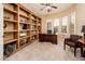 Home office with custom built-ins, a ceiling fan, and ample natural light from bay windows at 23216 N Gaviota Dr, Sun City West, AZ 85375