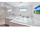 This bright bathroom features a jacuzzi tub, walk-in shower, tiled floors and walls, and a window at 2421 E Montebello Ave, Phoenix, AZ 85016