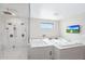 This bright bathroom features a jacuzzi tub, walk-in shower, tiled floors and walls, and a window at 2421 E Montebello Ave, Phoenix, AZ 85016