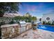 Stone outdoor kitchen features a built-in grill adjacent to the pool area and a soothing water feature at 2421 E Montebello Ave, Phoenix, AZ 85016
