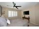 Comfortable bedroom featuring neutral tones, ceiling fan, and large windows with white shutters at 2424 E Aster Dr, Phoenix, AZ 85032