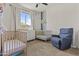 Bright Bedroom with two cribs, a white dresser, and a comfortable chair for relaxing at 24540 N 144Th Ave, Surprise, AZ 85387
