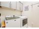 Laundry room with white Maytag washer and dryer, overhead storage cabinets, and neutral colored walls at 250 W Queen Creek Rd # 206, Chandler, AZ 85248