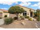 Charming single-story home featuring a well-manicured front yard with desert landscaping and a mature tree at 27030 W Escuda Dr, Buckeye, AZ 85396