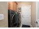 Functional laundry room featuring front-load washer and dryer with wood cabinets at 27030 W Escuda Dr, Buckeye, AZ 85396