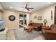 Stylish living room featuring tile flooring, a ceiling fan, a leather sofa, and sliding glass doors to the patio at 27030 W Escuda Dr, Buckeye, AZ 85396