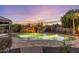 Serene backyard view showcasing a sparkling pool with a waterfall feature, surrounded by lush landscaping and a stone patio at 2782 E Citadel Ct, Gilbert, AZ 85298