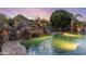 Backyard pool area features a grotto, waterfall, and lush landscaping under a colorful sky at 2782 E Citadel Ct, Gilbert, AZ 85298