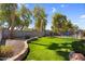 Serene backyard with manicured lawn, mature landscaping, privacy fence, and a glimpse of a sparkling pool beyond at 3443 E Thornton Ave, Gilbert, AZ 85297
