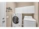 Modern laundry room featuring a front load washer and dryer, storage cabinets, and wall art at 3443 E Thornton Ave, Gilbert, AZ 85297