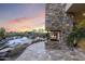 Inviting outdoor fireplace with stone surround, next to a refreshing pool with desert sunset backdrop at 36389 N 105Th Pl, Scottsdale, AZ 85262
