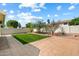 Enclosed backyard featuring a well-maintained lawn, mature trees, and a spacious stone-paved patio area at 4546 E Villa Rita Dr, Phoenix, AZ 85032