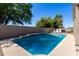 Backyard pool with a textured concrete patio, a decorative raised wall, and a patio seating area at 5811 W Irma Ln, Glendale, AZ 85308