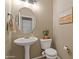 Elegant powder room with pedestal sink, round mirror, and neutral color scheme at 7010 W Downspell Dr, Peoria, AZ 85345