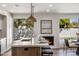 Modern kitchen features a quartz-topped island, sink, pendant lights and a cozy fireplace, creating an inviting space at 7520 E Valley View Rd, Scottsdale, AZ 85250