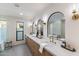 Luxurious main bathroom with dual sinks, quartz counters, gold fixtures, and arched mirrors at 7520 E Valley View Rd, Scottsdale, AZ 85250