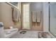 Toilet with tile floor, framed art, and modern privacy blinds at 7807 E Granada Rd, Scottsdale, AZ 85257