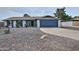 Inviting single-story home with gravel yard, a covered entry, and a blue two-car garage door at 815 E Paradise Ln, Phoenix, AZ 85022