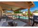 This covered patio overlooks a swimming pool, outdoor furniture, and the clear blue sky at 8402 W Laurel Ln, Peoria, AZ 85345