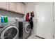 This laundry room offers both a washing machine and a dryer with overhead cabinets at 8402 W Laurel Ln, Peoria, AZ 85345