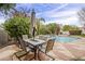 Patio with a dining table and umbrella, overlooking a pristine pool and lush landscaping creates a serene ambiance at 9442 N 118Th St, Scottsdale, AZ 85259