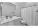 Bright bathroom features a white vanity with sink, toilet and shower with curtain at 9942 E Rotation Dr, Mesa, AZ 85212