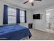 Bright bedroom with adjacent bathroom features a ceiling fan, neutral carpet and a bed with blue covers at 9942 E Rotation Dr, Mesa, AZ 85212