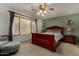 Comfortable main bedroom with a wooden bed frame, lamps, ceiling fan, and a window at 1101 S Hazel St, Gilbert, AZ 85296