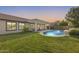 Expansive backyard showcasing a covered patio and sparkling pool with manicured lawn and privacy fencing at 11502 E Rafael Ave, Mesa, AZ 85212