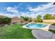 Beautiful backyard with lush green grass, a pool, and a waterfall feature at 11502 E Rafael Ave, Mesa, AZ 85212
