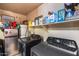 This functional laundry room has a washer, dryer, shelving, and mini refrigerator at 12048 W Dahlia Dr, El Mirage, AZ 85335