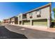 Townhouse complex with tidy landscaping, multiple garages, and a balcony under a clear blue sky at 1330 S Aaron -- # 218, Mesa, AZ 85209