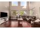 Bright living room featuring a two-story ceiling, large windows, hardwood floors, and comfortable seating at 13514 W Banff Ln, Surprise, AZ 85379