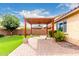 Relax on the brick patio under the covered pergola, overlooking the low-maintenance artificial turf backyard at 1437 E Flamingo Way, Gilbert, AZ 85297