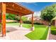 Backyard view of the brick patio and a pergola with lighting overlooking an artificial lawn at 1437 E Flamingo Way, Gilbert, AZ 85297