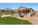 Backyard with a swimming pool, outdoor kitchen, fire pit, green lawn, and desert landscaping at 18051 W Port Royale Ln, Surprise, AZ 85388