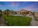 Expansive backyard with a pool, lush green lawn, mature trees, and an outdoor kitchen at 18051 W Port Royale Ln, Surprise, AZ 85388